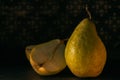 The pear is whole and cut against the background of old wallpaper. Photo in still life style. Front view close up.