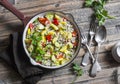Pearl barley with seasonal garden vegetables in pan on wooden background, top view. Zucchini, sweet pepper, squash and barley stew Royalty Free Stock Photo