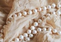 Pearl beads on beige draped fabric background