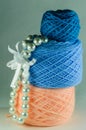 Pearl beads, pink ball of yarn, blue yarn ball and a small ball of blue yarn.