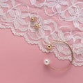 Pearl golden bracelet and stud earrings on white textile on pink background Royalty Free Stock Photo