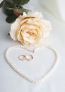 Pearl heart, a rose and wedding rings