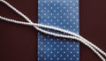 Pearl jewellery necklace and abstract blue polka dot background on chocolate backdrop