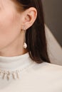 Pearl jewelry on the model. Earrings and necklace of white pearls on the neck and ears and a young girl in a white turtleneck