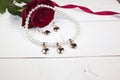 Pearl necklace with earring with golden hearts on white wood