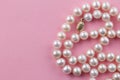 Pearl necklace with gold clasp on pink background