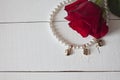 Pearl necklace with golden hearts on white wood