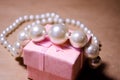 Pearl necklace on a pink box. Pearl jewelry. Imitation of pearls. Not a natural pearl. Bijouterie. Luxury and wealth