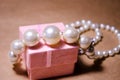 Pearl necklace on a pink box. Pearl jewelry. Imitation of pearls. Not a natural pearl. Bijouterie. Luxury and wealth