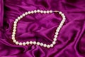 Pearl necklace on purple satin fabric background Royalty Free Stock Photo