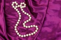 Pearl necklace on purple satin fabric background Royalty Free Stock Photo