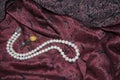 Pearl necklace, rose brooch on dark cherry silk