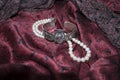 Pearl necklace, rose brooch and vintage Egyptian bracelet on dark cherry silk