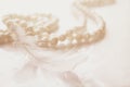 White feather in combination with a pearl necklace on a white bacground, close-up. Royalty Free Stock Photo