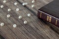 Pearls of great price and holy bible on wooden table