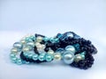 Pearls necklaces arranged in a pile on light blue background.