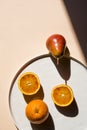 Pears and oranges with art shadows on a color background.