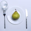Pears on a plate top view. next to it lie a fork. a glass of water is on the white table Royalty Free Stock Photo