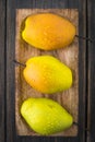 Pears of varying degrees of ripeness in brown craft wooden plate