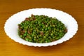 Tasty Peas with ham on a white plate and wooden background. Close up view