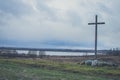 Peasant wooden cross on the mountain near the river bank, lake.