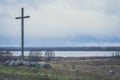 Peasant wooden cross on the mountain near the river bank, lake.