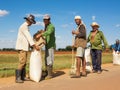 Peasants collect the rice after drying it on the asphalt