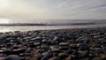 Pebble beach with small pebbles and sea waves. Action. Sea surface on the wild pebble beach, silent evening on the