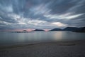 Pebble beach at sunset with moving clouds and silky sea