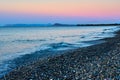 Pebble beach with waves on a sunset. Crete, Greece. Royalty Free Stock Photo
