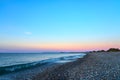 Pebble beach with waves on a sunset. Crete, Greece. Royalty Free Stock Photo