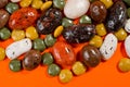 Pebble-dragee with apricots, chocolate, mandarin and marzipan. Tasty, bright, shot on an orange background