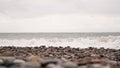 Pebble stones on the shore close up in the blurry light in the distance Royalty Free Stock Photo