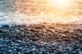 Pebble stones on the shore close up in the blurry sunset light in the distance background