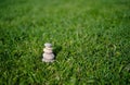 Pebble tower with blurry green grass background,Stack of Zen rock stones on fields ,Stones pyramid with daisy on lawn at park Royalty Free Stock Photo