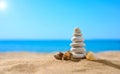 Pebble tower with small seashells on the sunny beach against the backdrop of the sea. Summer theme. Royalty Free Stock Photo