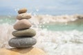 Pebble tower on sunny beach sea wave splashing water balance pyramid harmony peace of mind Royalty Free Stock Photo