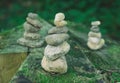 Pebble towers in a forest. Balanced stones in a pile on the wooden background covered with moss Royalty Free Stock Photo