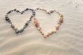 Pebbles arranged in shape of two hearts on sand beach ripples Royalty Free Stock Photo
