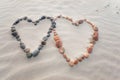 Pebbles arranged in shape of two hearts on sand beach ripples Royalty Free Stock Photo