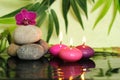 Pebbles arranged in zen lifestyle on the left with an orchid at the top and three lit pink candle Royalty Free Stock Photo