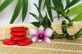 Pebbles arranged in Zen lifestyle with a orchid on the right side of bamboo twisted on wooden floor and foliage backg Royalty Free Stock Photo