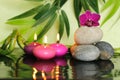 Pebbles arranged in Zen lifestyle on the right with an orchid at the top and pink candles lit Royalty Free Stock Photo