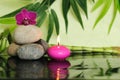 Pebbles laid on the left out in zen lifestyle with an orchid at the top and a pink candle lit