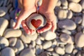 pebbles with a painted heart in the hands of a child on the background of a pebble beach