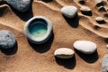 Pebbles and stone bowl with water on sand