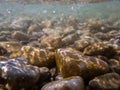 Pebbles stone underwater below water surface near lake shore, natural scene Royalty Free Stock Photo