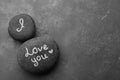 Pebbles with words I LOVE YOU and little heart on grey table, flat lay