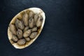 Pecan Nuts with the Nutshell in Eco Natural Banana Leaf Plate on Black Stone Background Surface with Free Space Royalty Free Stock Photo