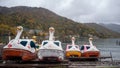 Pedal duck boats beside Chuzenji lake on mountain with colorful autumn trees and cloudy sky background